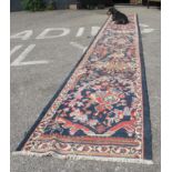 A Persian runner, decorated with repeating floral designs, on a dark blue ground  28" x 178"