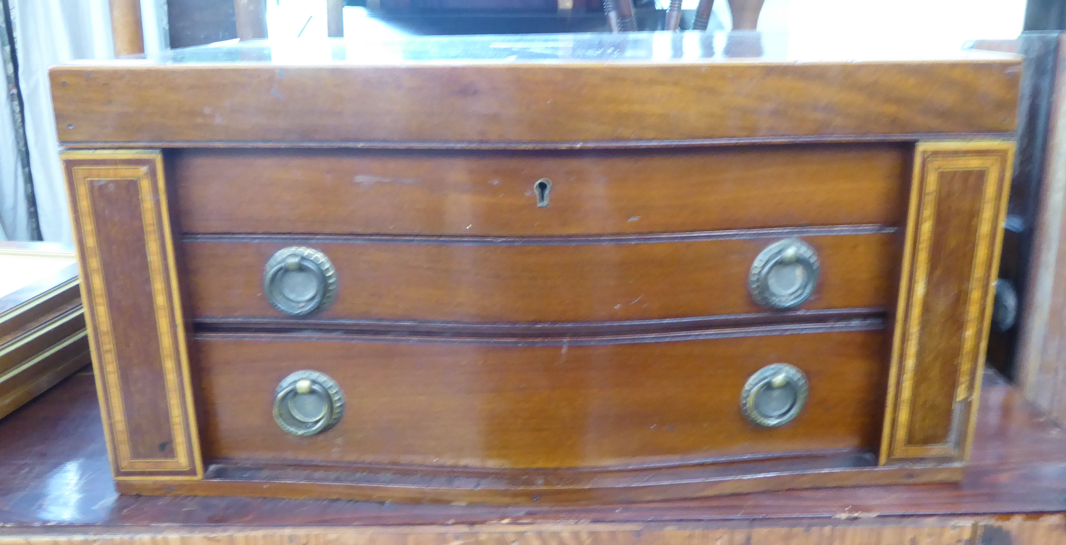 A circa 1910 string inlaid, crossbanded mahogany serpentine front, partially fitted, three drawer