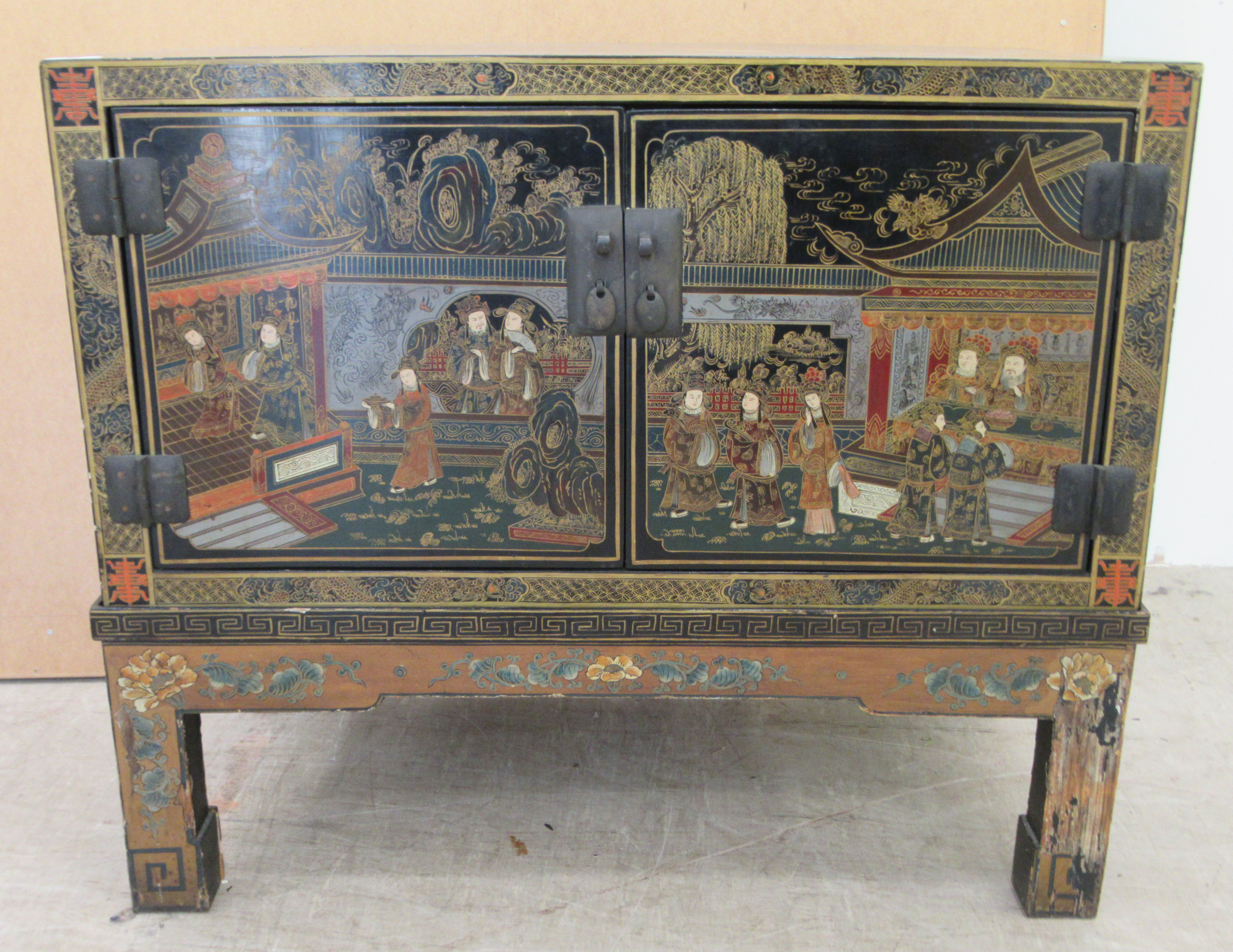 A 20thC Japanese black lacquered low cabinet on stand with two doors, decorated with traditional