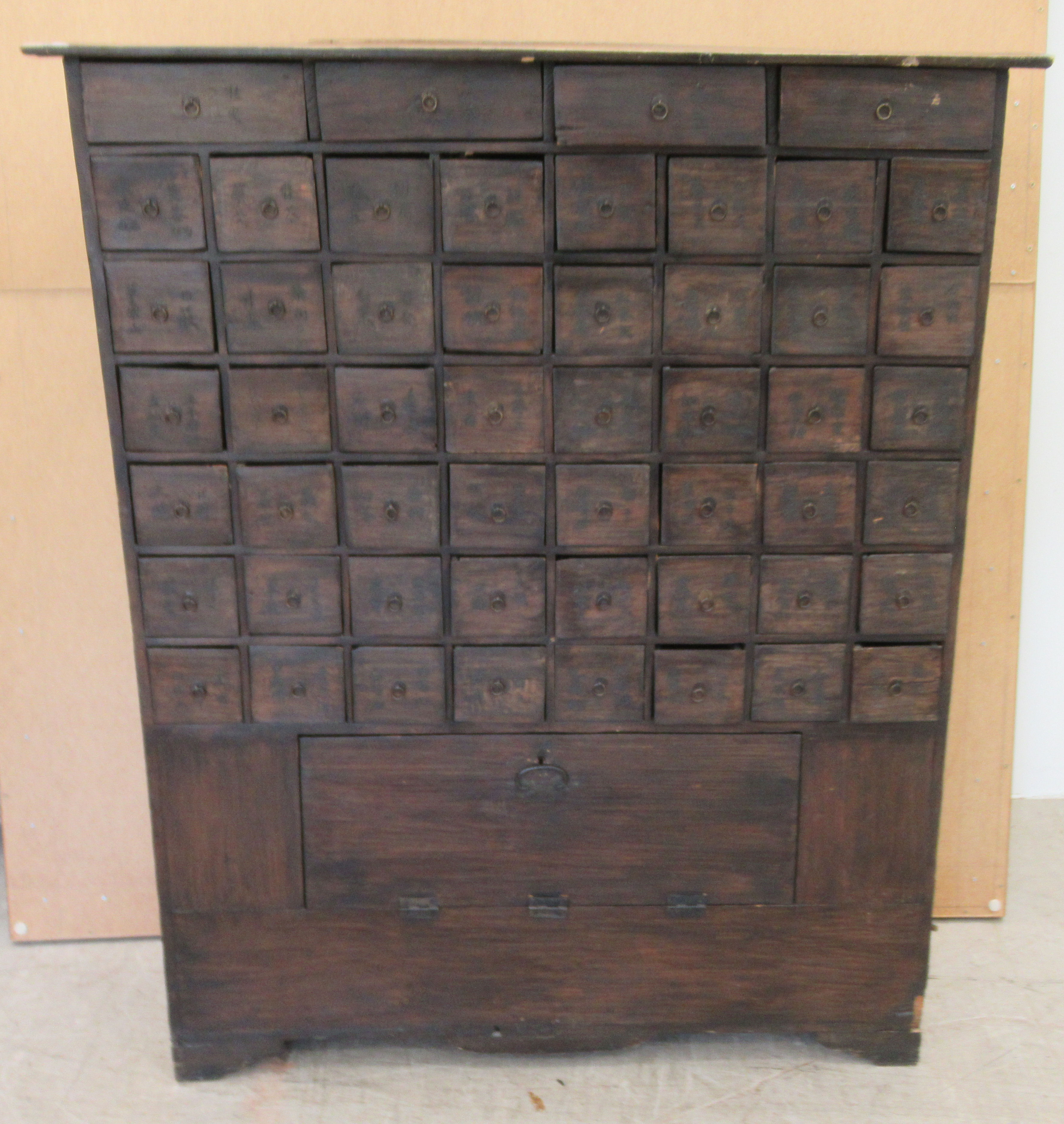 A 20thC Chinese stained pine medicine cabinet with an arrangement of fifty-two drawers, over a