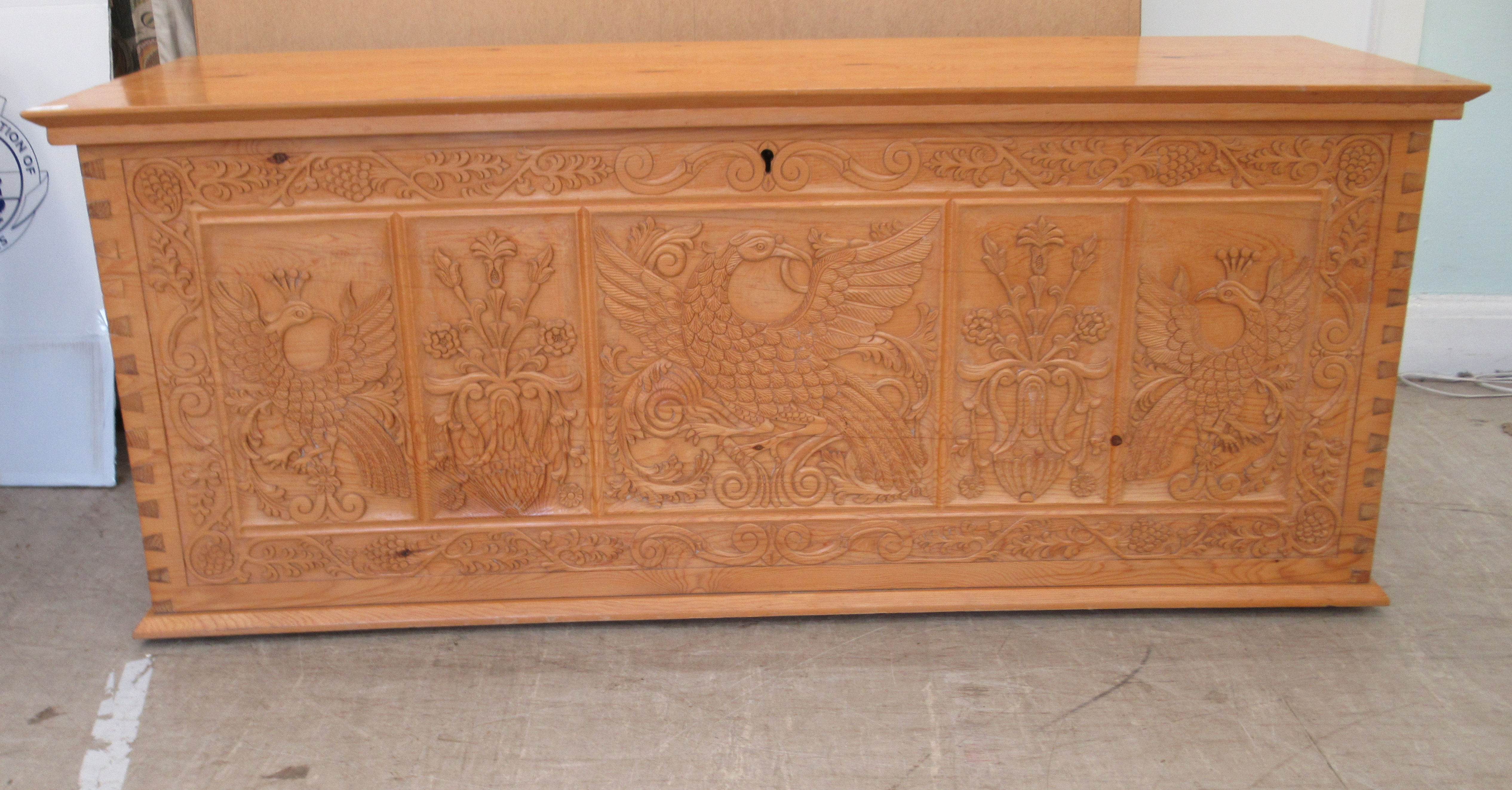 A modern Asian inspired pine blanket chest with straight sides and a hinged lid, over an exotic bird