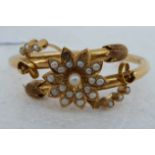 A 15ct gold crossover bangle, joined with a flower and trailing vines, set with pearls