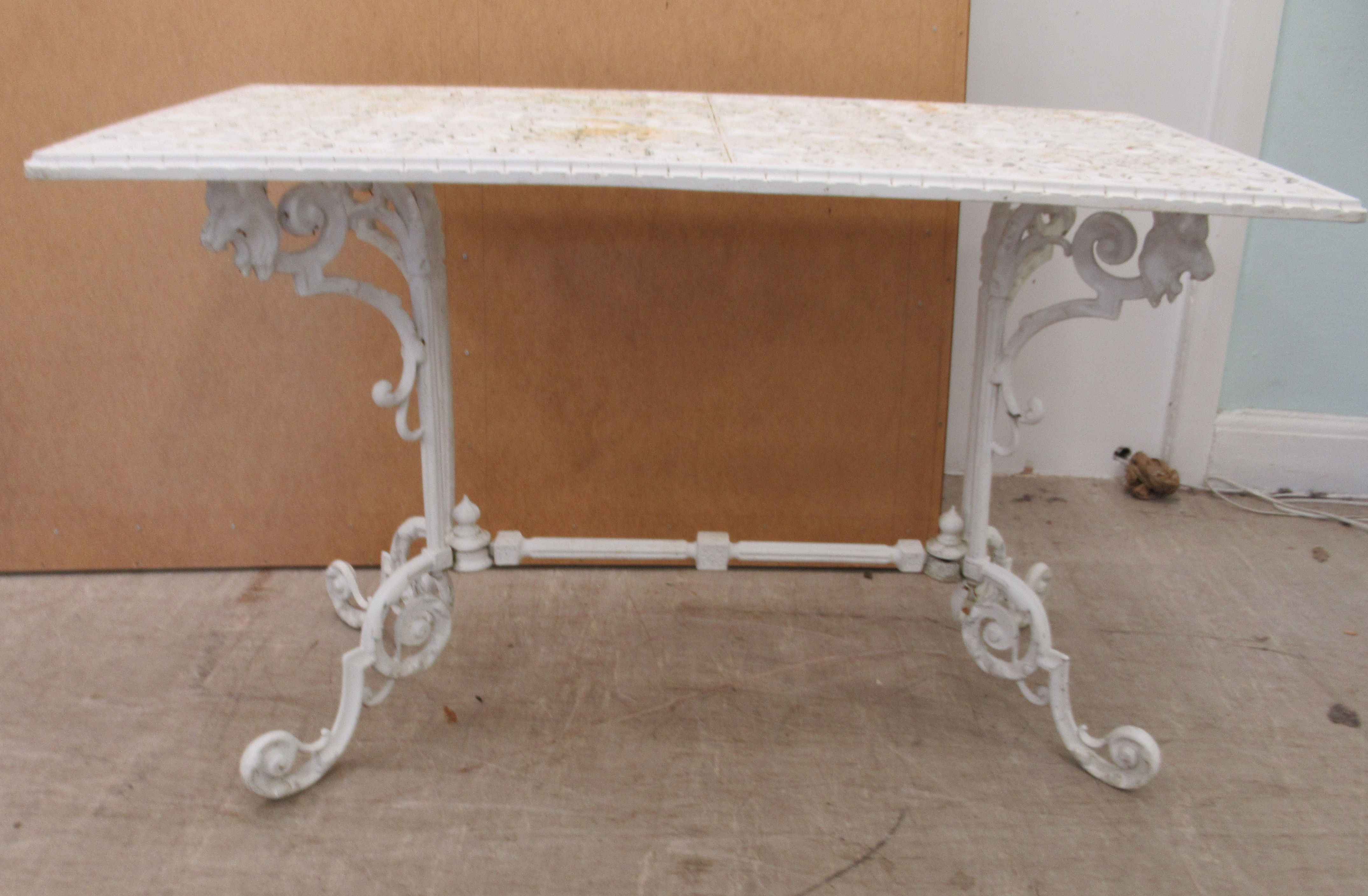 A Victorian style white painted cast metal terrace table, raised on pillar supports and C-scrolled
