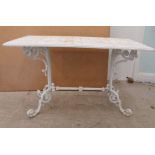 A Victorian style white painted cast metal terrace table, raised on pillar supports and C-scrolled