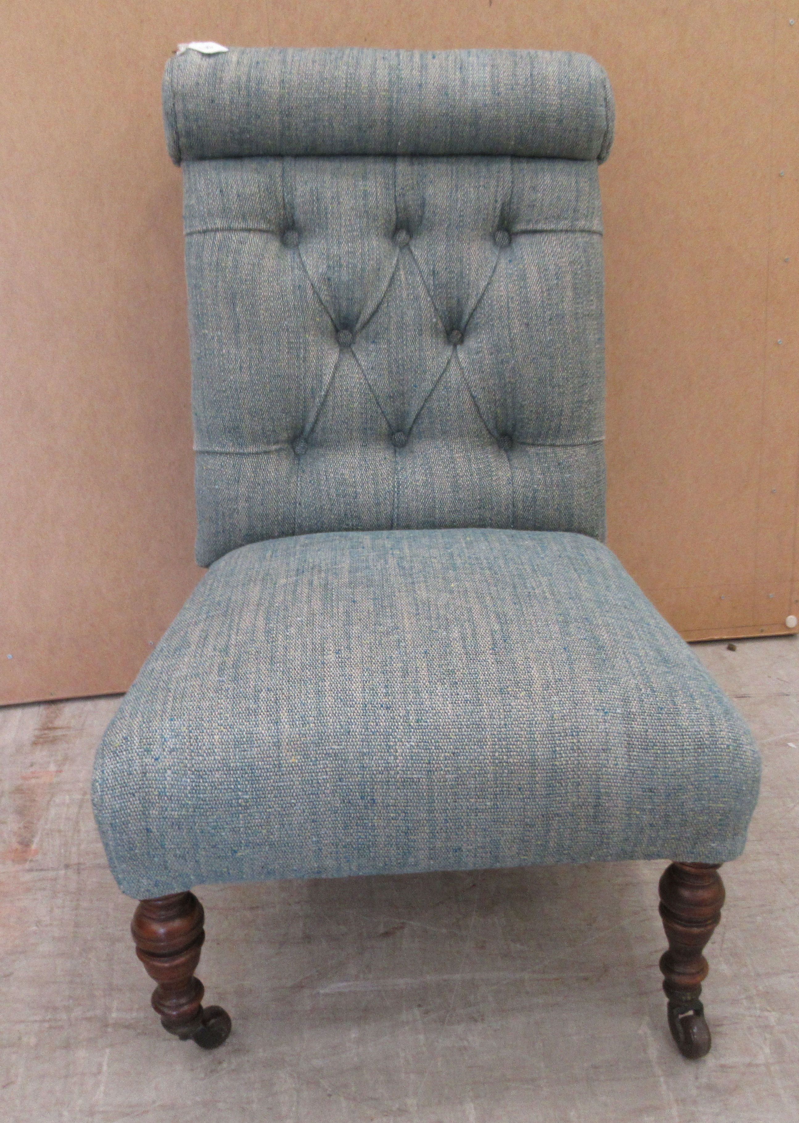 An Edwardian nursing chair, later upholstered in multi-coloured fabric, raised on turned forelegs