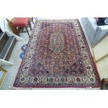 A Persian rug, decorated with a central motif, profusely bordered by stylised floral designs, on a