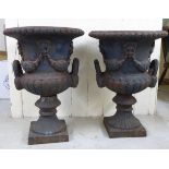 A pair of 19thC cast iron twin handle pedestal urns, on square plinths  23"h