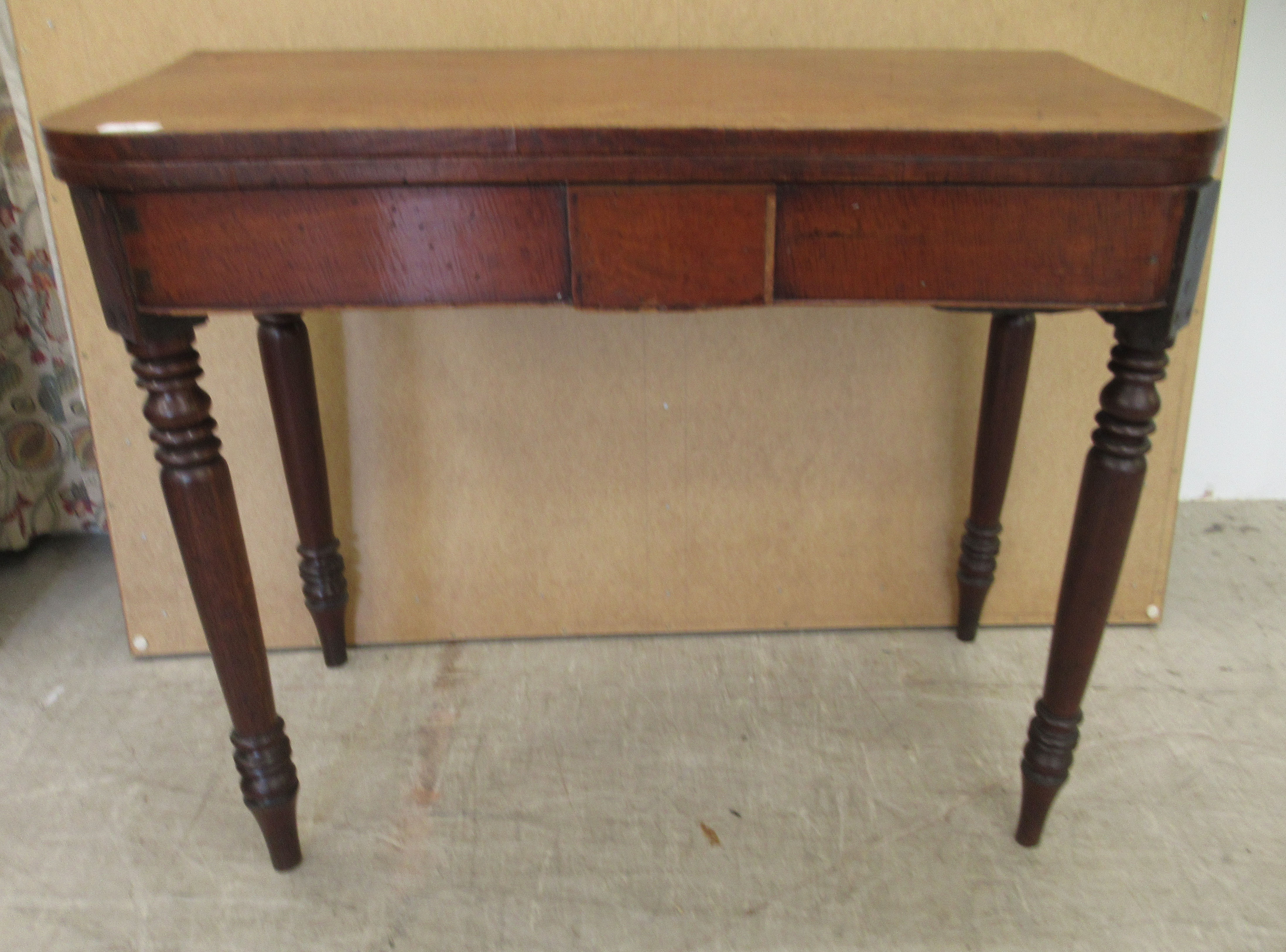 A George III mahogany bow front tea table, the rotating foldover top raised on ring turned,