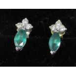 A pair of 18ct white gold earrings, set with a green marquise cut stone, surmounted with three