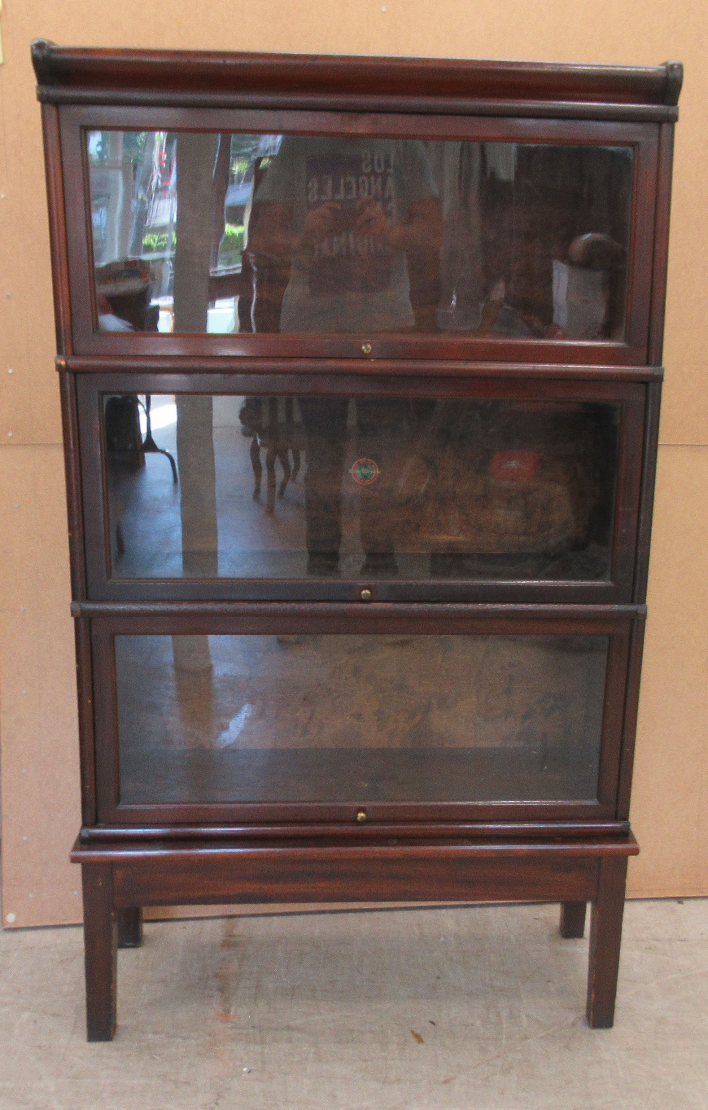 An early 20thC Globe Wernicke mahogany and glazed three section bookcase on stand, raised on