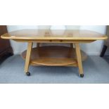 An Ercol and later adapted and married blonde elm, beech and pine two tier coffee table, on assorted