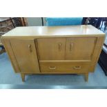 A G-Plan light oak sideboard with an arrangement of doors and a drawer, raised on square, tapered