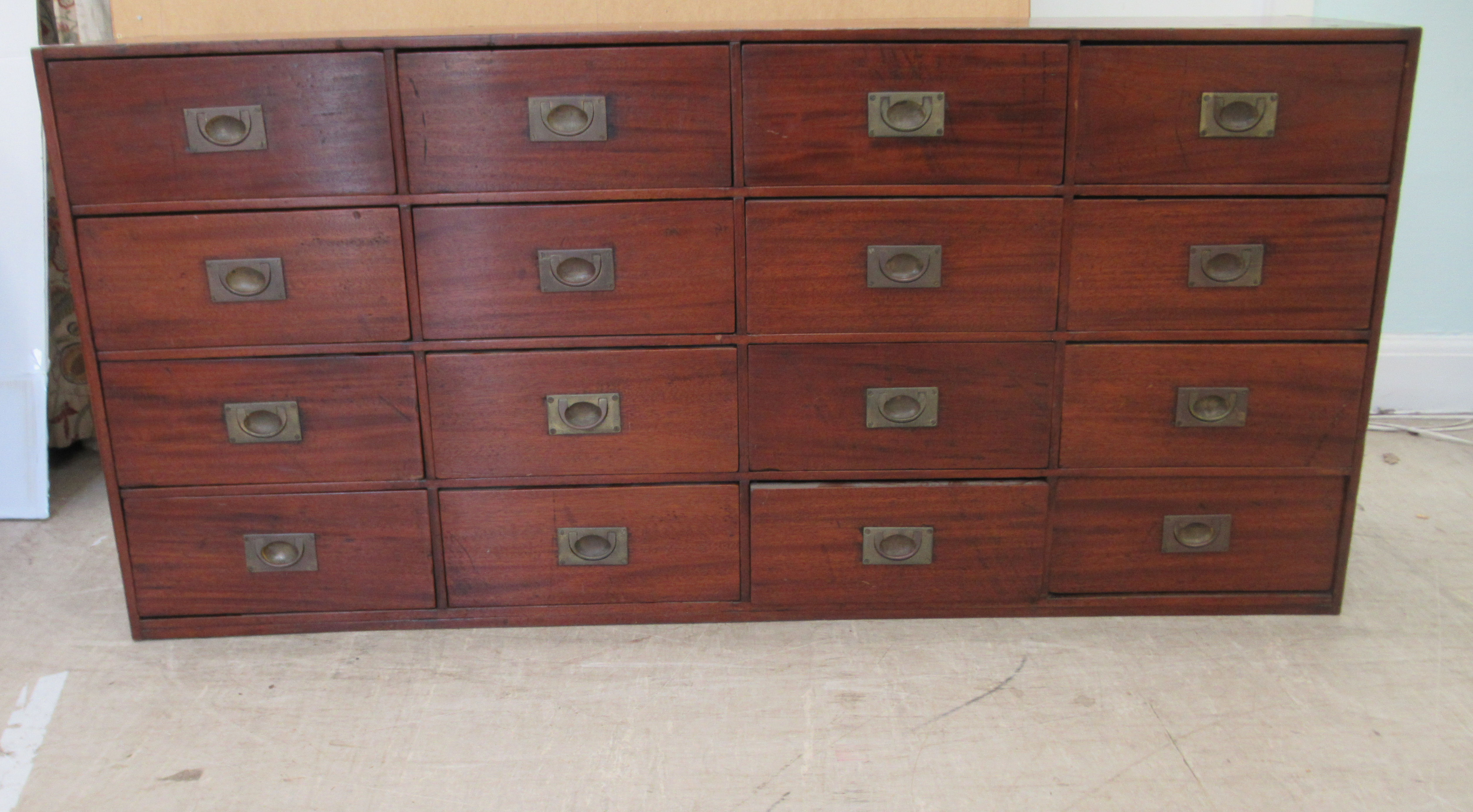 An early 20thC Chinese stained pine sixteen drawer cabinet, on a plinth  30"h  63"w