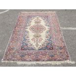 A Persian rug, decorated with a central motif, bordered by floral designs, on a multi-coloured