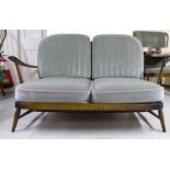 A dark stained beech and elm framed two person low settee with green fabric upholstered cushions