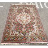 A Persian rug, decorated with a central serpentine outlined motif, bordered by feather and floral