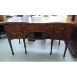 A George III string inlaid mahogany serpentine front sideboard with a central drawer and a left hand