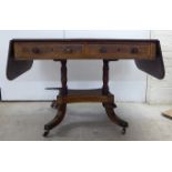 An early Victorian string inlaid mahogany sofa table with two frieze drawers, raised on a splayed