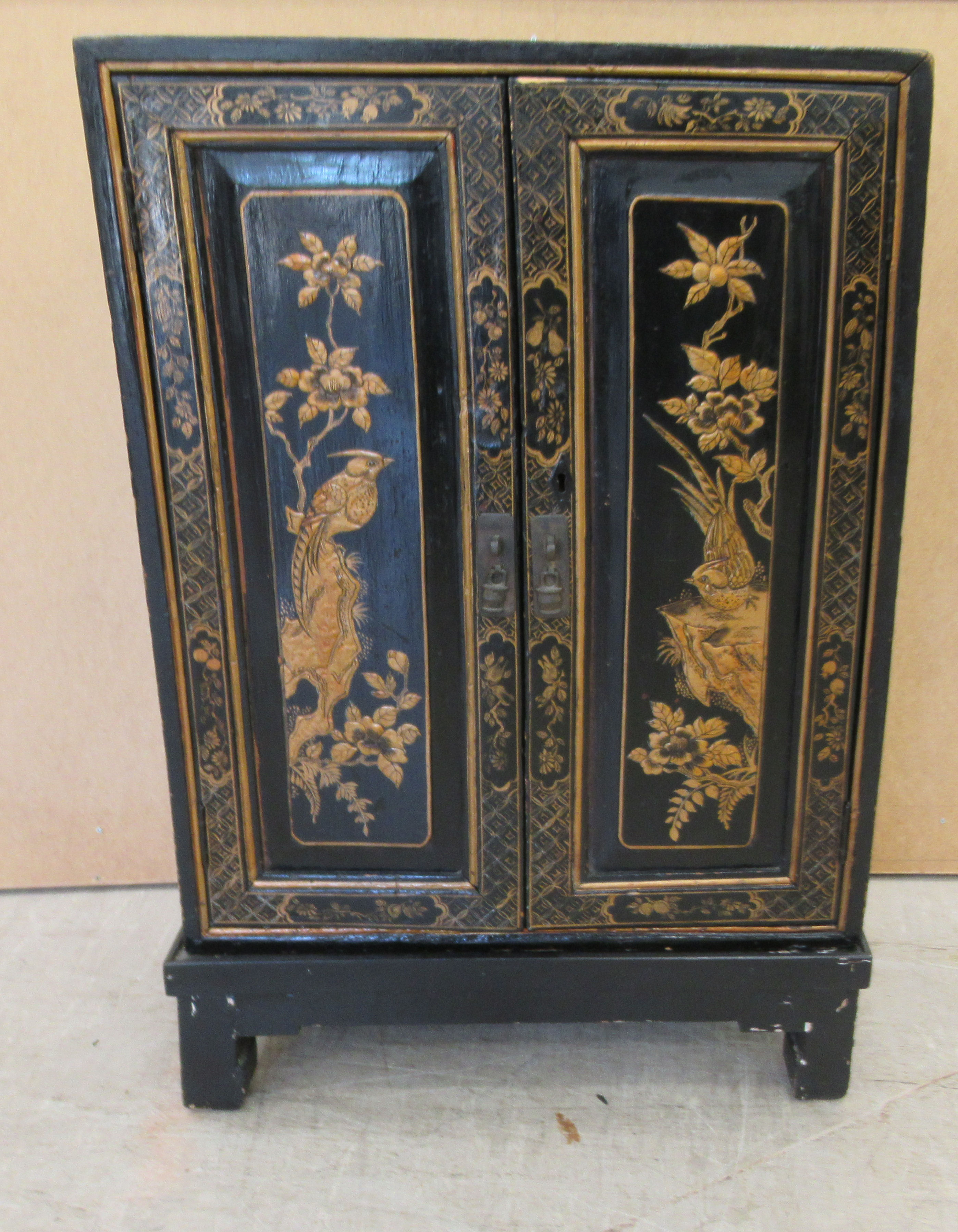 A 20thC Japanese black lacquered low cabinet on stand, decorated with birds and foliage  32"h  21"w