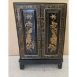 A 20thC Japanese black lacquered low cabinet on stand, decorated with birds and foliage  32"h  21"w