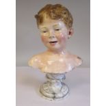A 20thC painted pottery bust, a smiling boy, on a turned, faux marble socle  13"h