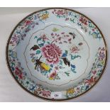 A Chinese porcelain charger, having a raised border, decorated in famille rose with flora, fruit,