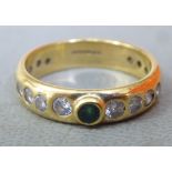 An 18ct gold ring, set with an emerald and eighteen diamonds