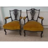 A pair of Edwardian mahogany framed open arm salon chairs, upholstered in old gold fabric, raised on
