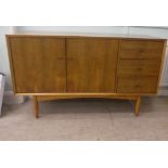 A Vanson teak sideboard with a pair of cupboard doors, adjacent to three drawers, raised on turned