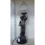 A weathered spelter novelty table lamp, fashioned as Cupid holding a flaming torch, on a turned