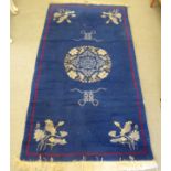 A Chinese washed woollen rug, decorated with flora on a navy blue ground  68" x 40"
