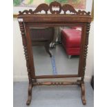 An early 20thC stained beech and mahogany framed firescreen with a mirrored panel, on bobbin