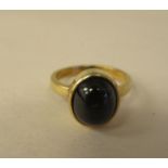 A gold coloured metal ring, set with a star sapphire