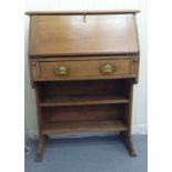 A 1920s honey coloured oak students desk, the lockable hinged, full front enclosing a pigeonhole