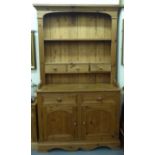 A modern waxed pine two part cottage dresser, the upper part with open shelves and box drawers,