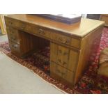 A mid 20thC walnut veneered desk with a brown rexine scriber, over three frieze drawers, raised on