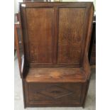 A mid 20thC stained oak hall settle with a high, twin panelled, level back and hinged box seat  31"w