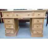 A modern waxed pine desk, comprising three inline drawers, raised on a pair of three drawer