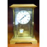 A modern mantel clock with a glazed, lacquered brass and oak case; the 8 day exposed striking