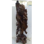 A modern Asian carved hardwood table lamp, in the form of a standing elderly man, holding a staff,