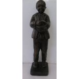 A vintage carved and stained wooden figure, a standing boy holding a basket, on a chamfered