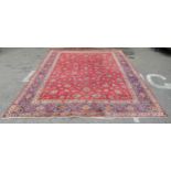 A Persian carpet, decorated with flora and foliate designs, on a mainly red ground with a dark