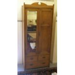 An Edwardian oak wardrobe with twin doors, enclosing a hooked and railed interior, over two short/