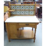 An early 20thC washstand, the tiled and marble superstructure on a light oak base, raised on