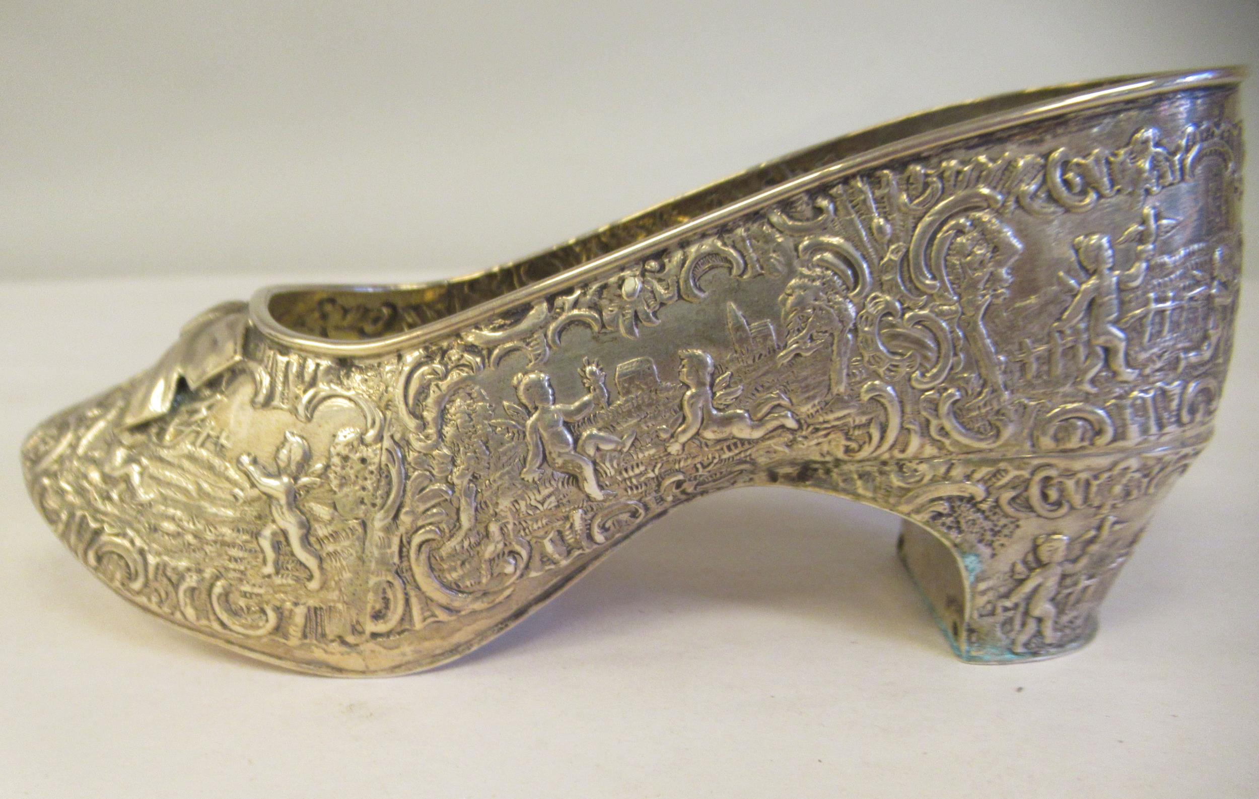 A Dutch silver coloured metal ornament, in the form of a lady's shoe, allover cast and chased with - Image 2 of 6