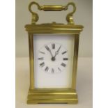 A lacquered brass cased carriage clock with bevelled glass and decorative ceramic flank panels and a