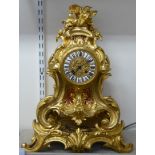 A 20thC Victorian style gilt metal cased mantel clock; the 8 day movement faced by a china Roman
