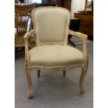 A modern cream wash painted beech framed elbow chair, upholstered in green fabric, raised on