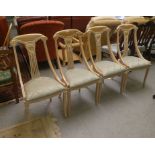 A set of four modern cream wash painted beech framed dining chairs, raised on sabre forelegs
