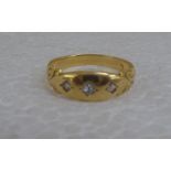 A yellow metal three stone, rubover set diamond ring